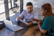 © wavebreak3 - Diverse coworkers wearing business attire reviewing document with pen, laptop in office