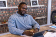 © wavebreak3 - African american man in shirt taking notes with pen at office desk with tablet charts