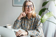 © shurkin_son - Picture of cheerful female of 60s in casual clothes and glasses enjoying her leisure time using advanced technologies and talking to AI chatbot, discussing funny topics, asking questions