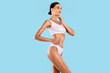 © Prostock-studio - Fitness, Diet, Skincare Concept. Portrait Of Half-turned Smiling Tender Slim Lady With Perfect Ideal Body Shape Touching Soft Skin On Her Neck With Hand Posing Isolated On Blue Studio Background
