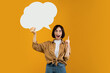 © Prostock-studio - Aha moment. Inspired lady having idea, holding blank speech bubble and pointing finger up, showing empty space for your text, standing over orange studio background