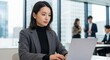 © Stingray_Japan - モダンなオフィスでノートパソコンに向かって仕事をするジャケットとタートルネック姿の20代日本人女性社員