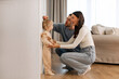 © Home-stock - Kids Growth Progress. Loving parents fixing height of sweet little daughter child, setting hand on wall over kids head