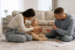 © Home-stock - Warm Family Time. Happy parents playing with little daughter, teach to count on fingers while sitting on the floor in living room