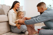 © Home-stock - Loving father making present to his child girl, giving dress and trying it on his daughter, family sharing joyful moment in living room