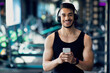 © Prostock-studio - Sporty Young Arab Man Wearing Wireless Headphones Using Smartphone At Gym, Happy Middle Eastern Male Athlete Relaxing With Mobile Phone After Workout Training In Modern Fitness Club, Copy Space