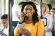 © Prostock-studio - Urban Lifestyle. Smiling African American woman on train listening to music on smartphone. Young lady using cell phone app and wireless headphones to listen to audiobook, enjoying travel
