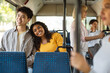 © Prostock-studio - Portrait of happy loving multiethnic couple taking bus sitting on seat together, young black lady leaning on asian guy shoulder, looking out window, enjoying travel or ride on public vehicle