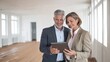 © AdPremium - Smiling mature business colleagues discussing project on digital tablet in empty modern office room
