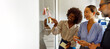© Moon Safari - Colleagues discussing and brainstorming ideas using colorful adhesive notes on glass wall in modern office