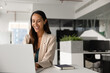 © fizkes - Happy woman typing on laptop keyboard sits at desk in coworking office, feel satisfied while exchange e-mails with client or colleague, assisting remotely, working online on project or presentation
