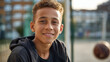 © Kateryna - Faceless teenage biracial boy smiles at outdoor sports field youth athletics recreational space adolescent happiness sporting venue defocused background with copy space
