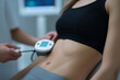 © tania_wild - Medical professional uses device on patient's abdomen for body contouring treatment