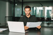 © Stock 4 You - Latin manager businessman with paperwork in office. Smiling young male entrepreneur business man analyst holding document contract, working at laptop computer doing online trade market tech research.