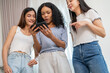 © Art_Photo - Happy diverse group of multiethnic female friends looking at smartphone and laughing at home, young asian and african american women enjoying social media video, friendship and technology concept