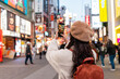 © Kittiphan - Young female tourist taking a photo of tourist and nightlife areas in Dotonbori district in Osaka, Japan