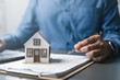 © Garun Studios - Mortgage and real estate finance concept showing house model on documents with professional signing, representing home loan calculation, property investment, interest rates, and financial planning.