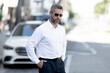 © Volodymyr - Man walking city street summer travel. Man standing confident near cars urban. Man looking serious during journey portrait. Man enjoying weekend vacation lifestyle.