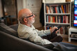 © Halfpoint - Elderly man watching television alone at home.