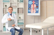 © Pixel-Shot - Mature doctor with clipboard in medical office