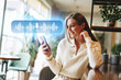 © fotofabrika - Woman using smartphone to send voice message while sitting in cafe during the day