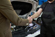 © pressmaster - Caucasian middle aged man in suit shaking hands with Caucasian young adult male mechanic in uniform near open car hood in auto repair shop, confirming successful service agreement