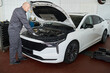 © pressmaster - Middle aged Caucasian man inspecting engine compartment of modern sedan in auto repair shop, standing beside open hood and focusing on vehicle maintenance task