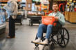 © Serhii - Smiling customer using wheelchair buying groceries in supermarket