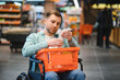 © Serhii - Customer in wheelchair checking grocery shopping list in supermarket