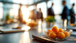 © ABF_MATEO - Bowl of oranges on a table during a business meeting, with blurred figures in the background, creating a warm & productive ambiance.