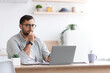 © Prostock-studio - Concentrated mature caucasian male businessman with beard in glasses look at laptop at kitchen interior. Covid-19 quarantine, modern education, social distance, work at home remote and freelance