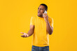 © Prostock-studio - Furious African American Man Talking On Phone Gesturing Emotionally In Anger Having Negative Cellphone Conversation Standing Over Yellow Studio Background. Mobile Communication Problem