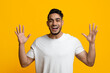 © Prostock-studio - Emotional handsome millennial middle eastern man with stylish hair and beard raising hands up and smiling, expressing amazement on yellow studio background, human gestures and emotions concept