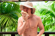 © Ranta Images - Scandinavian Tourist Man Eating Durian Outdoors with Tropical Leaves Background