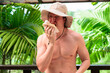 © Ranta Images - Scandinavian Tourist Man Eating Durian Outdoors with Tropical Leaves Background