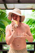 © Ranta Images - Scandinavian Tourist Man Eating Durian Outdoors with Tropical Leaves Background