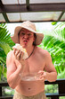 © Ranta Images - Scandinavian Tourist Man Eating Durian Outdoors with Tropical Leaves Background