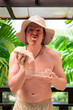 © Ranta Images - Scandinavian Tourist Man Eating Durian Outdoors with Tropical Leaves Background