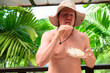 © Ranta Images - Scandinavian Tourist Man Eating Durian Outdoors with Tropical Leaves Background