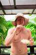 © Ranta Images - Scandinavian Tourist Man Eating Durian Outdoors with Tropical Leaves Background
