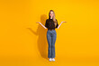 © deagreez - Young female model stands against a bright yellow background with a friendly smile and open arms casual fashion for lifestyle advertising and shopping use