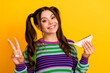 © deagreez - Young girl with pigtails wearing a striped sweater smiles and holds a sandwich against a bright yellow background in a casual cheerful lifestyle photo