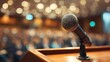 © Faris - Microphone on a wooden podium in a dimly lit auditorium with blurred audience