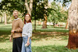 © Bliss - Lively couple enjoying a spring day stroll through a lush green park