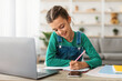 © Prostock-studio - Happy girl student using laptop for distance education, doing homework or enjoying conference video call, watching webinar tutorial, writing notes, studying with teacher, having virtual lesson