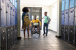 © Wavebreak Media - African American students supporting wheelchair student, holding backpacks and notebooks in hallway