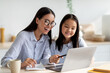 © Prostock-studio - Happy asian mom helping her studying daughter, looking at laptop screen together, sitting in kitchen interior. Excited school girl using computer, having online lesson while coronavirus pandemic