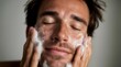 © Studio Zenith - Homme souriant qui se lave le visage avec de la mousse nettoyante
