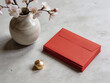 © Anim - Chinese New Year: Stack of red envelopes with cherry blossoms and golden decoration on gray table