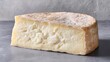 © Emilio - Artisan cheese wedge on neutral stone surface showing creamy interior and natural rind. Minimalist food concept with rustic texture and gourmet dairy